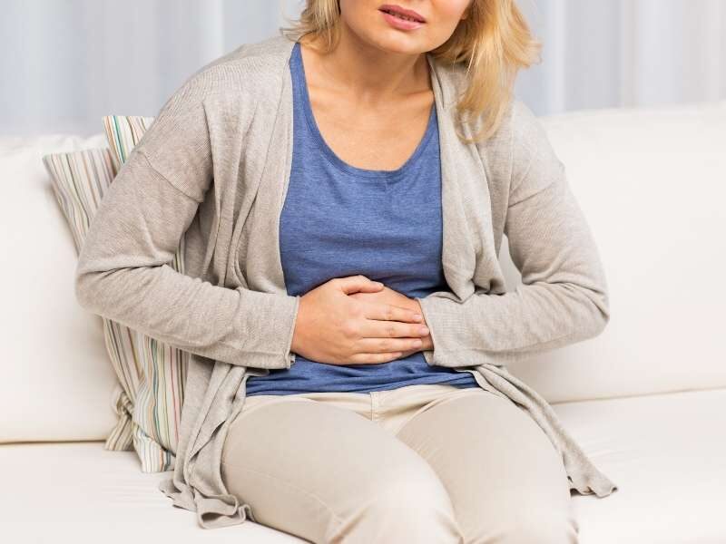 Mulher com a mão na barriga com disbiose.