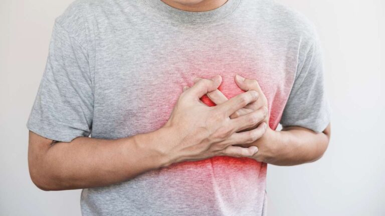 Homem com ataque cardiaco infarto com a mão no peito.