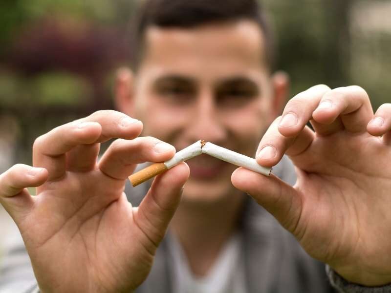 Homem quebrando cigarro ao meio.