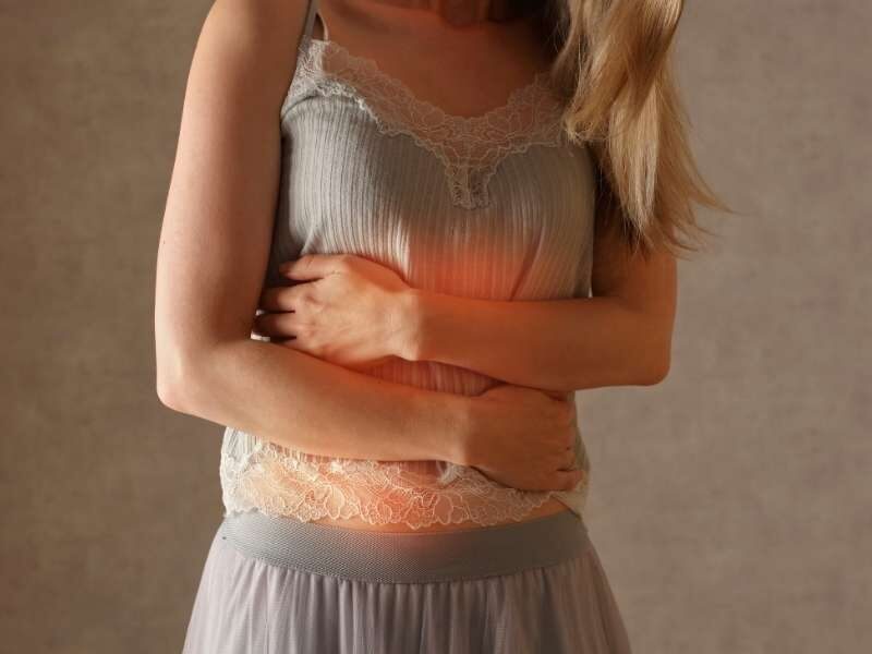 Mulher com as mãos na barriga.