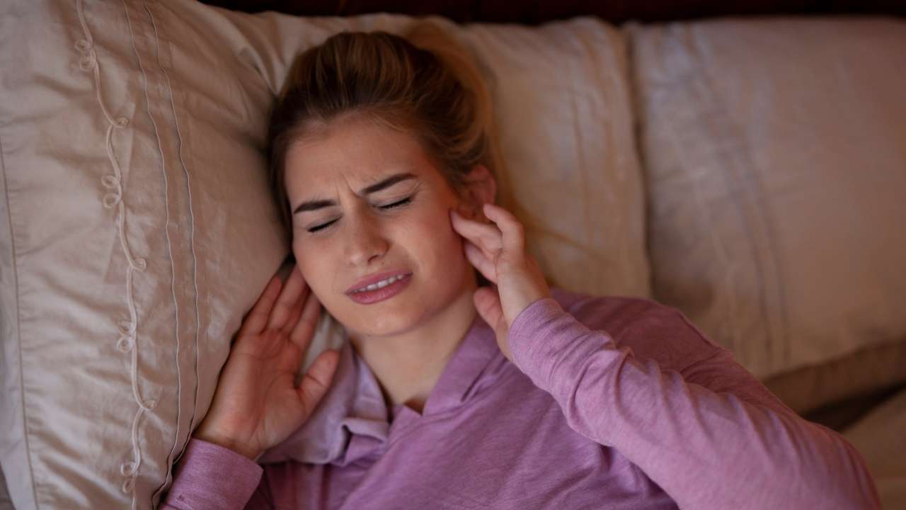 Mulher com dor na ATM articulação temporomandibular.