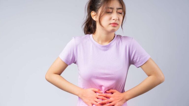 Mulher com a mão na barriga com gastrite.