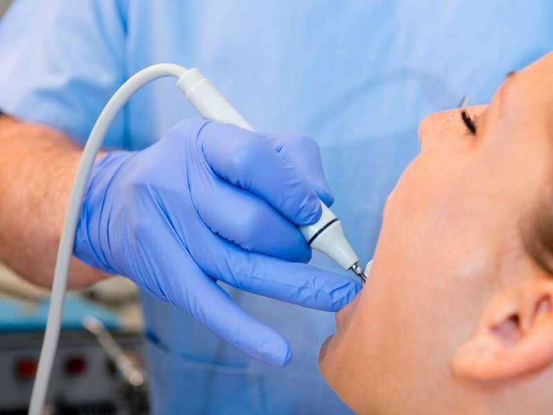 Dentista fazendo limpeza de tártaro em paciente.
