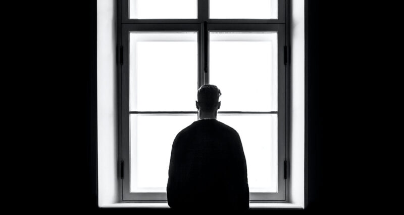 homem depressivo em frente à janela como sinal de agitação mental