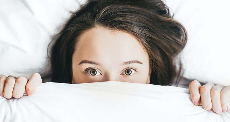 mulher deitada na cama com os olhos abertos