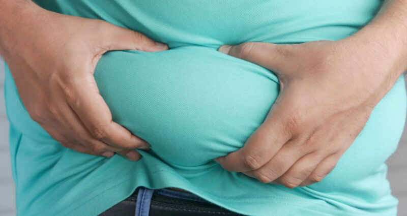 homem obeso com as mãos na barriga.