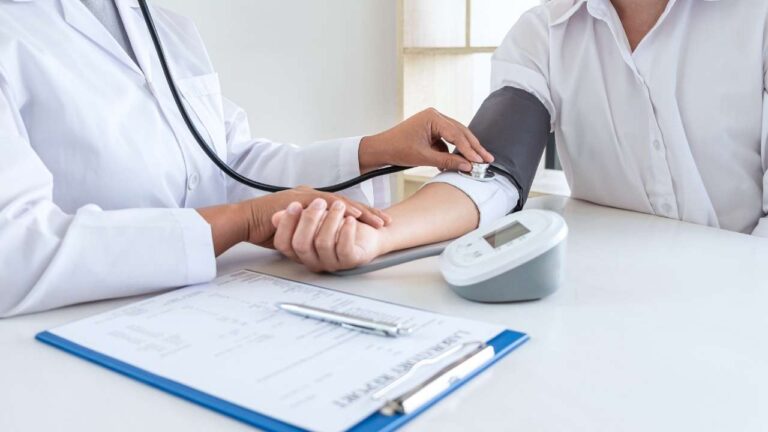 Medica aferindo níveis de hipertensão em paciente.