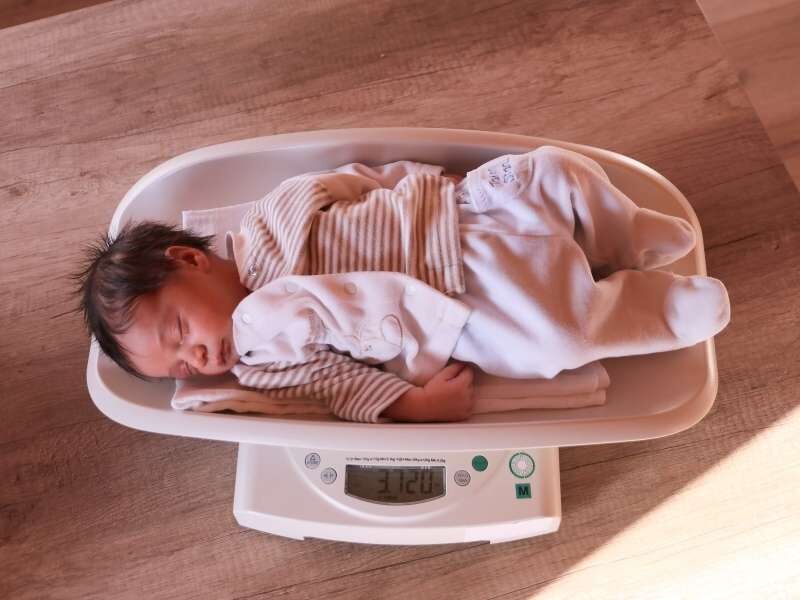 Bebê em balança para verificar seu peso.