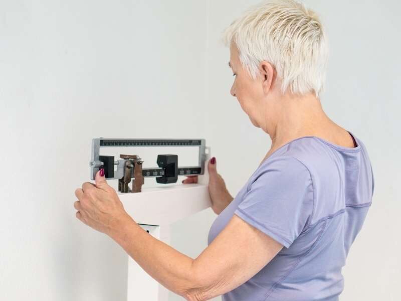 Mulher idosa verificando seu peso corporal.